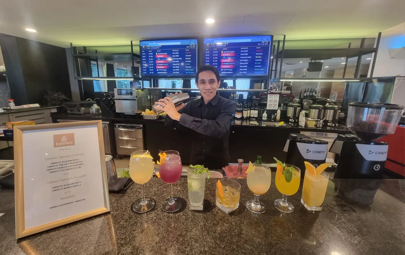 Barstylez bartender shaking a cocktail behind a bar lined with Emirates signature cocktails and mocktails